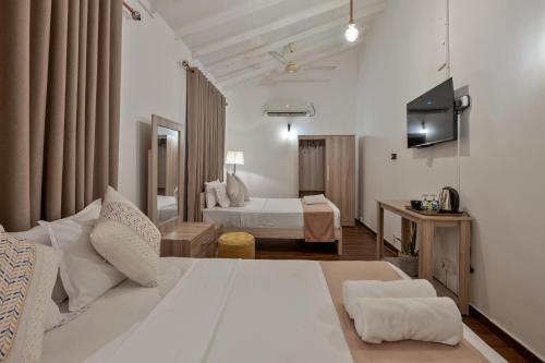 um quarto de hotel com uma grande cama branca e uma televisão em The Empyrean Airport Transit Hotel em Katunayaka