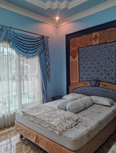 a bedroom with a large bed with blue walls and windows at Sentral Villa Trawas in Trawas
