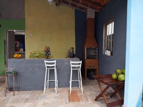 a kitchen with a bar with stools and a table at Recanto Barcelos de Mel com piscina e churrasqueira in Camamu