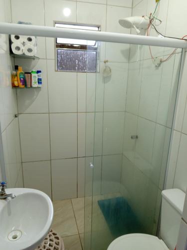 a bathroom with a shower and a toilet and a sink at Recanto Barcelos de Mel com piscina e churrasqueira in Camamu