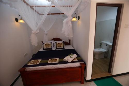 a small bedroom with a bed and a mirror at Ella Ninestars Lodge in Ella