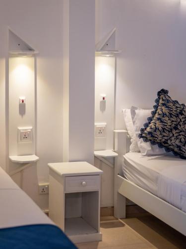 a bedroom with a bed and two nightstands with lights at The Empyrean Airport Transit Hotel- 5 Mins from the Airport, Free Airport Pick or Drop, 24 Hr Front Desk in Katunayaka