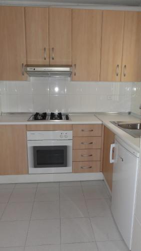 a kitchen with wooden cabinets and a stove top oven at Apartamentos Golf Center in Roquetas de Mar