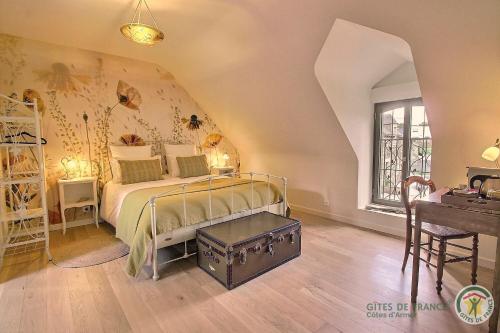 a bedroom with a bed and a table and a desk at La metairie in Plédèliac