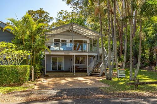 a home with palm trees in front of it at Reflections in Smiths Lake