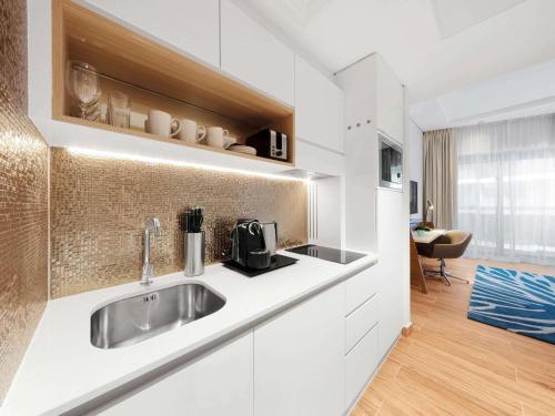 a kitchen with white cabinets and a sink at Adagio Premium The Palm in Dubai
