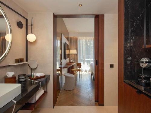 a bathroom with a sink and a room with a desk at L'Esquisse Hotel & Spa Colmar - MGallery Collection in Colmar