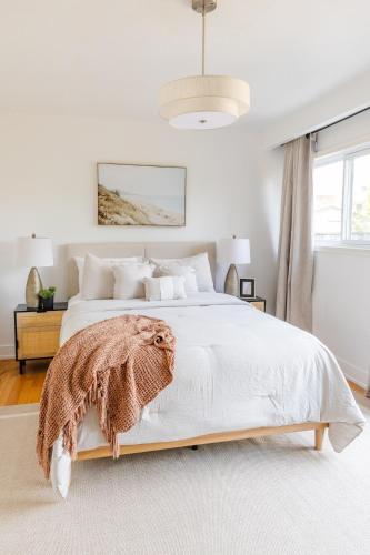 a white bedroom with a bed with a blanket on it at Private 2-BR Suite w Patio in Mississauga