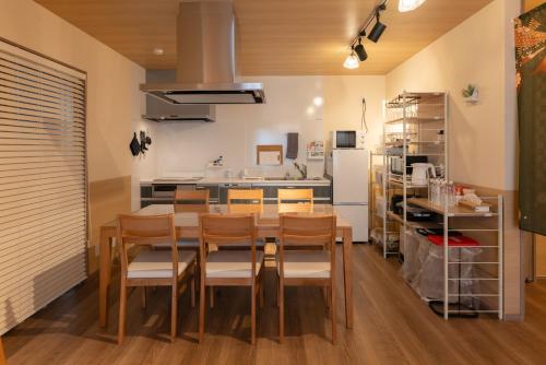 a kitchen with a table and chairs and a refrigerator at Somnus豊田 ペットOK 最大宿泊人数12名!1棟貸切の宿 in Toyota