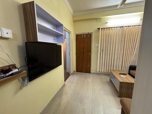 un salon avec une télévision à écran plat fixée au mur dans l'établissement H&S Apartment, à Pokhara