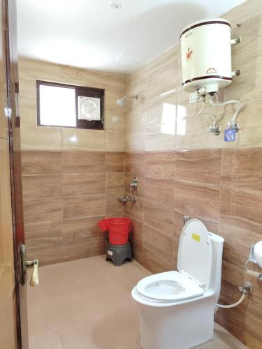 a small bathroom with a toilet and a window at Varuni Gd Hotel Mcleodganj in McLeod Ganj
