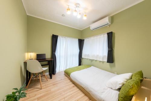 a bedroom with a bed and a desk and a window at いっぷく in Yokosuka