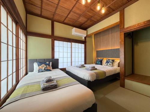 two beds in a room with windows at nestay villa tokyo ueno in Tokyo