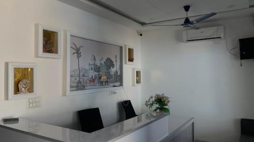 a room with a white wall with paintings and chairs at Shreeramyadham vrindavan in Vrindāvan