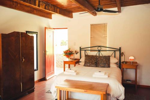 a bedroom with a bed and a table in it at Wilgewandel Holiday Farm & Day Restaurant in Oudtshoorn