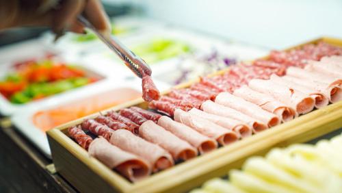 una persona sta cucinando degli hot dog su una griglia di Sugar Marina Hotel - NAUTICAL - Kata Beach a Kata Beach