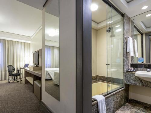 een hotelkamer met een badkamer met een bad en een slaapkamer bij Grand Mercure Curitiba Rayon in Curitiba