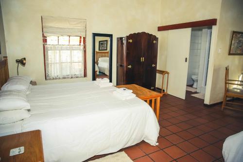 a bedroom with a large white bed in a room at Wilgewandel Holiday Farm & Day Restaurant in Oudtshoorn