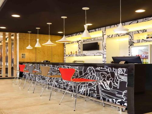 a bar with red chairs and a wall with graffiti at Ibis Guaxupe in Guaxupé