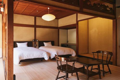 a bedroom with two beds and a table and a tableasteryasteryasteryasteryastery at 宿 -Shuku- in Inuyama