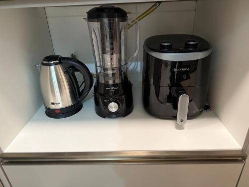 a blender and a coffee maker on a shelf in a refrigerator at Apartamento moderno na praia da palhoça c garagem in Palhoça