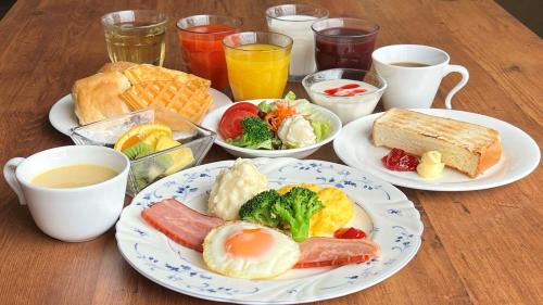 a table with plates of breakfast foods and drinks at Fukui Manten Hotel Ekimae in Fukui