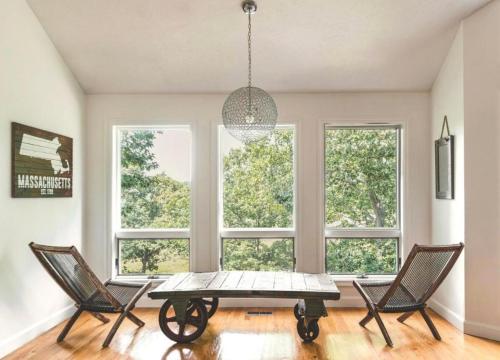 グロスターにあるLuxury Vacation Accommodation in the Coastal Town of Gloucester, Massachusettsのテーブルと椅子と窓のあるダイニングルーム