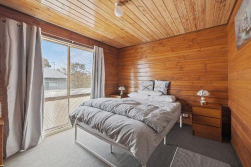 a bedroom with a bed in a room with a window at Neptune's Nook in Cape Paterson