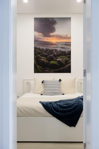 a bedroom with a bed with a painting on the wall at Casa Pedra de Sal in Ribeira Grande