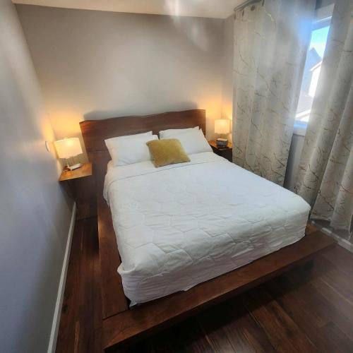 a bedroom with a bed with two lamps and a window at Modern Family Home with guest heat garage, Pet-Friendly!- NO BASEMENT in Edmonton