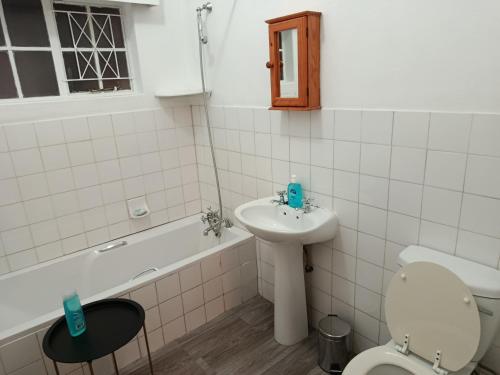 um banheiro com pia, vaso sanitário e banheira em Serendipity-on-Symmonds Cottage em Howick