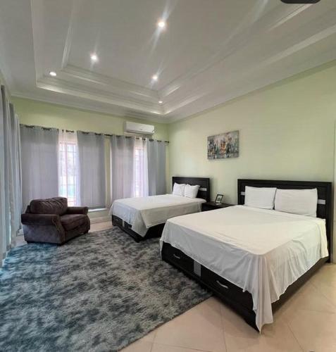 Un dormitorio con dos camas y un sofá y una silla. en C-Roy Estate, en Kupuis