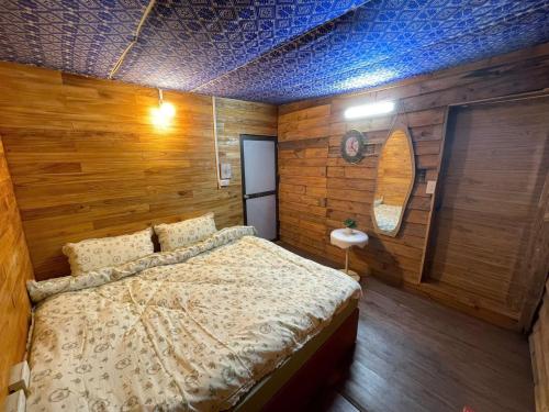 a bedroom with a bed in a room with wooden walls at Chà Homestay in Bắc Yên