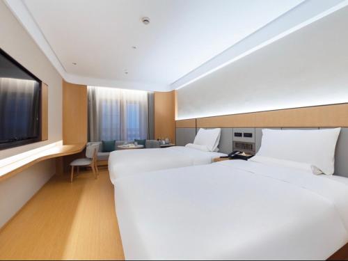 a hotel room with two beds and a flat screen tv at JI Hotel Shanghai International Tourism Resort Chongxi Road in Nanhui