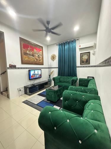 a living room with green furniture and a flat screen tv at Homestay Bandar Sejahtera in Pokok Sena