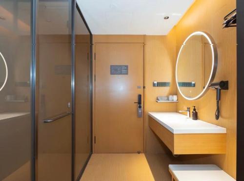 a bathroom with a shower and a sink and a mirror at JI Hotel Shanghai International Tourism Resort Chongxi Road in Nanhui