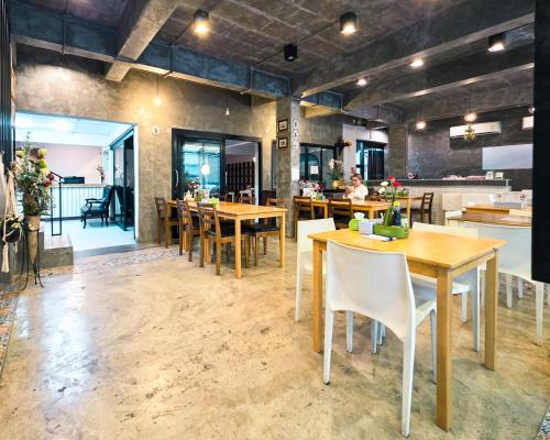 a restaurant with wooden tables and white chairs at Thepmongkol House in Bangkok