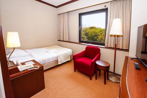 a hotel room with a bed and a red chair at Okayama International Hotel in Okayama
