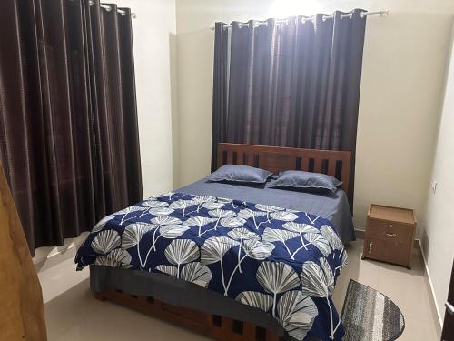 a bedroom with a bed with a blue and white comforter at Vathika Villa in Sultan Bathery