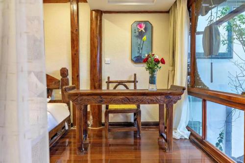 a bathroom with a table with a vase of flowers on it at Mengtianhu Inn in Lijiang