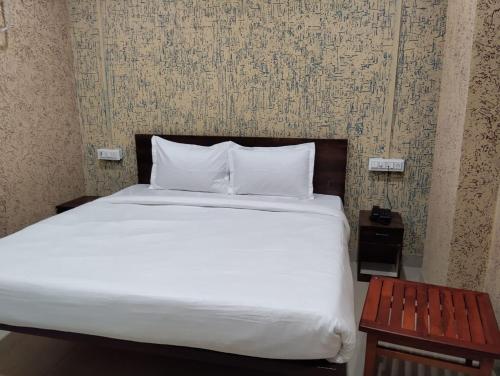 Una cama con sábanas blancas y almohadas en una habitación. en Hotel Vishnu Inn, en Rewa