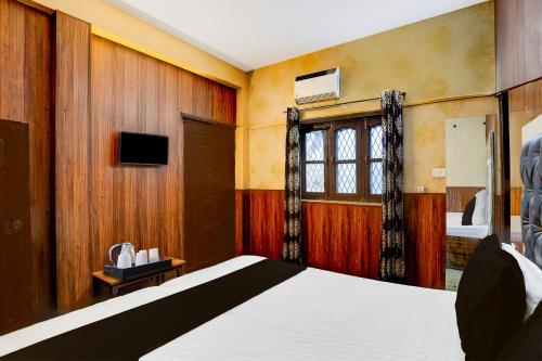 a bedroom with a bed and a window and a tv at Super Hotel O Dehradun City Centre in Dehradun