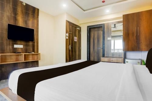 a bedroom with a white bed and a flat screen tv at Super Townhouse Lighthouse Beach Formerly Neel Sagar in Puri