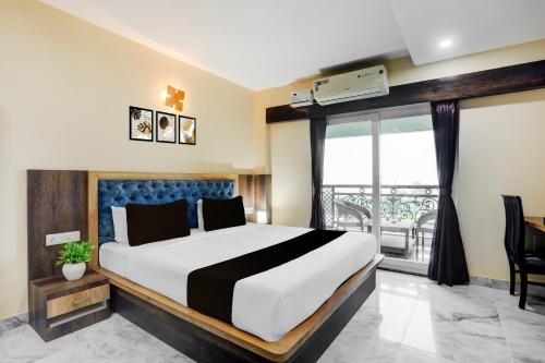 a bedroom with a large bed and a balcony at Super Townhouse Lighthouse Beach Formerly Neel Sagar in Puri