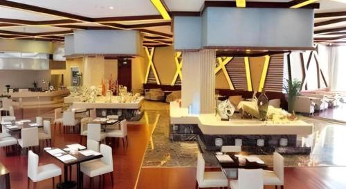 a restaurant with white tables and white chairs at Ramada Plaza by Wyndham Shaowu in Liaojiapai