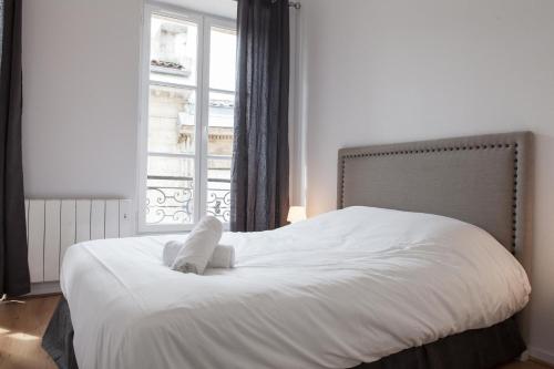 een slaapkamer met een wit bed en een raam bij Grand Théâtre Bright Apartment in Bordeaux