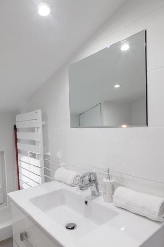 une salle de bain blanche avec un lavabo et un miroir dans l'établissement Grand Théâtre Bright Apartment, à Bordeaux