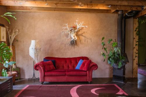 a red couch in a living room with a wall at CASA DE COUGLETTA - Artist retreat, stunning views in Santa Fe