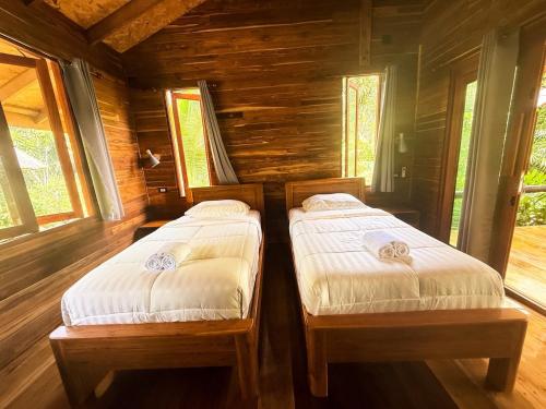 two twin beds in a wooden room with windows at Cocoa Home in Ban Ko Phrao