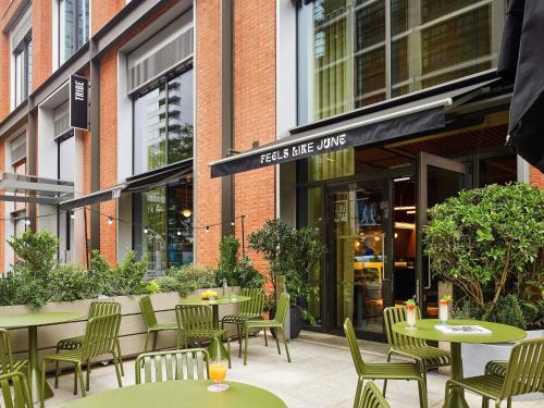 een restaurant met tafels en stoelen voor een gebouw bij TRIBE London Canary Wharf in Londen